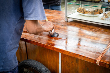 a carpenter varnishes a piece of wood with his hands