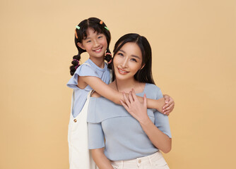 happy mother day. Adorable sweet young asian mother with cute little daughter hugging isolated on nude color background.