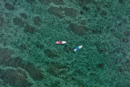 Aerial view of people with a SUP (stand up paddle) along Flic En Flac beach shoreline, Riviere Noire, Mauritius.