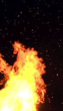ultra slow motion high speed shot of fire flames and glowing ash particles on black background - vertical video for reel and story