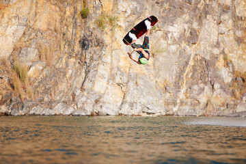Man, wakeboarding and lake for jump in air, sport and fitness for speed in summer sunshine. Person,...