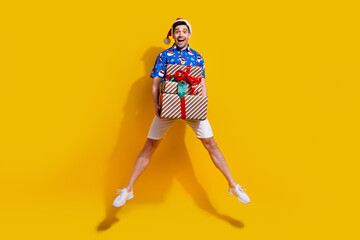 Full body photo of impressed overjoyed person jumping arms hold pile stack festive giftbox isolated on yellow color background