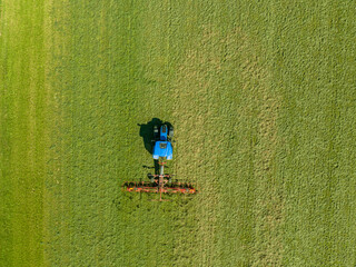 Aerial view of tractor working on a grass field. Concept of farming.