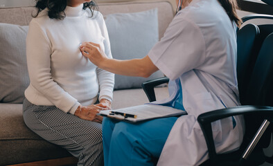 Asian doctor woman visited patient woman to diagnosis and check up health at home or private hospital. Female patient explain health problem and symptoms to doctor .Health care premium service at home