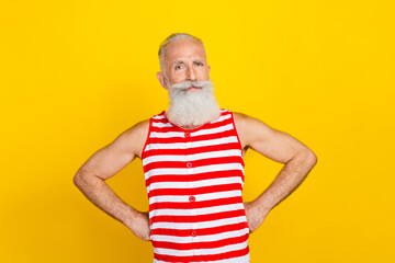 Photo of positive cool senior man wear red striped swimsuit hands arms waist isolated yellow color background
