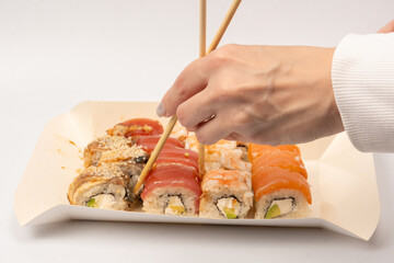 Food delivery. A box with sushi rolls in woman hands isolated.
