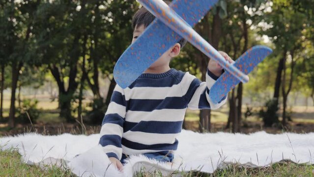 boy plays with a toy plane in the park with his older sister.