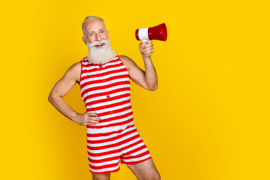 Photo of funky old man wear oldschool striped swimsuit hold megaphone and announce free cocktails party isolated on yellow color background - Powered by Adobe