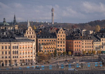 Old town Gamla Stan at the square Kornhamnstorg, skyline with tele tower Kaknästornet, blue subway...
