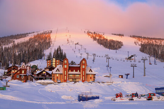 Sheregesh ski resort in Russia, picturesque sunrise, pink cloud on sky, white snow slopes and trails, view on mountain Green (mount Zelenaya), hotels, lift stations, Russia, Siberia. Panoramic
