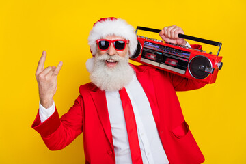 Photo of cool attractive santa dressed red suit tie enjoying boom box songs showing hard rock sign isolated yellow color background