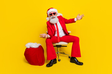 Full body photo of excited positive person sit chair huge gifts sack isolated on yellow color...