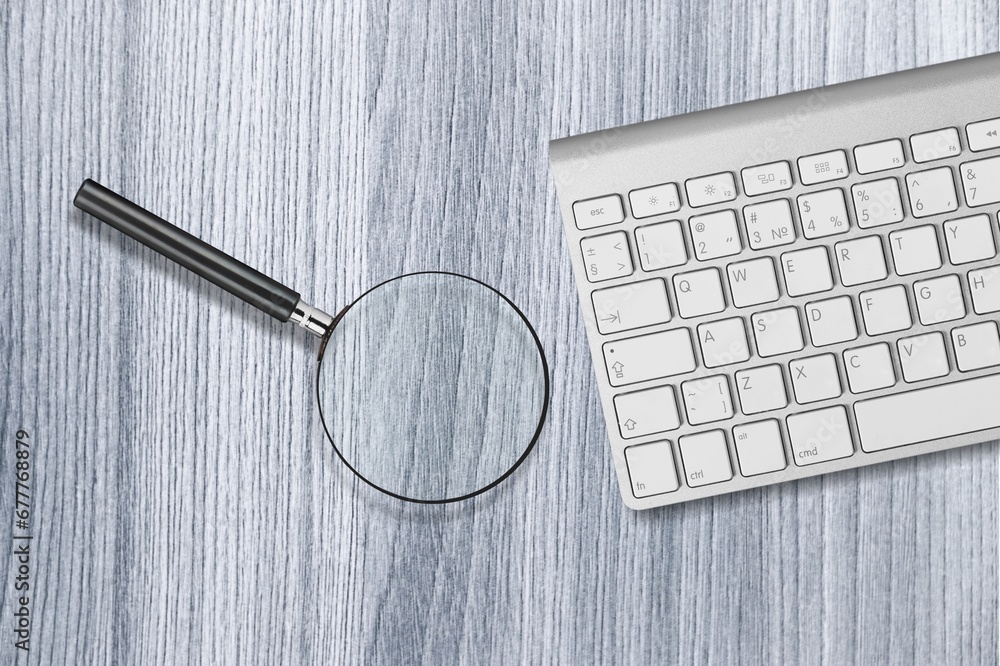 Poster the magnifying glass and computer keyboard on desk