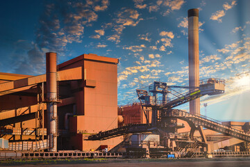 Loading iron ore conveyor machine in steel industry at sunset