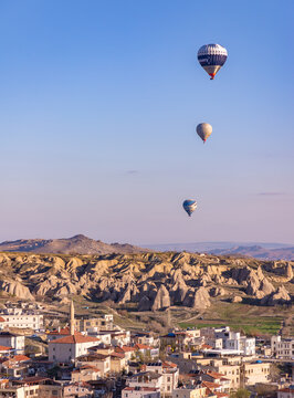 Goreme, Cappadocia, Turkey - April 14, 2023: A picture of hot air balloons flying over the town of Goreme at sunrise.