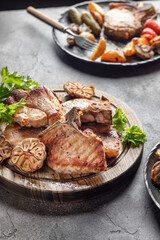 Grilled roasted bbq pork stake served with vegetables on brown table background. Party table