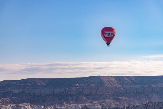 Goreme, Cappadocia, Turkey - April 14, 2023: A picture of a hot air balloon flying over the Goreme Historical National Park at sunrise.