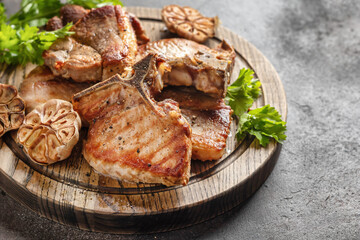 Grilled roasted bbq pork stakes served on wooden board on brown table background. Appetizing food, text space