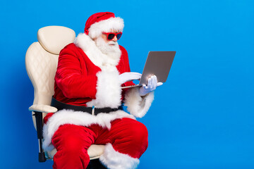 Photo portrait of retired old man sit armchair work remotely dressed stylish santa claus costume...
