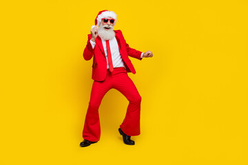 Fototapeta na wymiar Full length photo of cheerful cute man pensioner dressed red suit santa hat dancing having fun isolated yellow color background