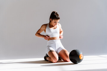 Obraz premium Young female athlete training in a gym using sport equipment. Fit woman working out . Concept about fitness, wellness and sport preparation.