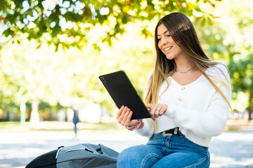 Young woman sitting on the ground and using a tablet computer