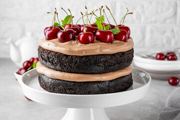 Naked Black forest cake, Schwarzwald pie. Cake with dark chocolate, cream and cherry on a gray concrete background. Copy space