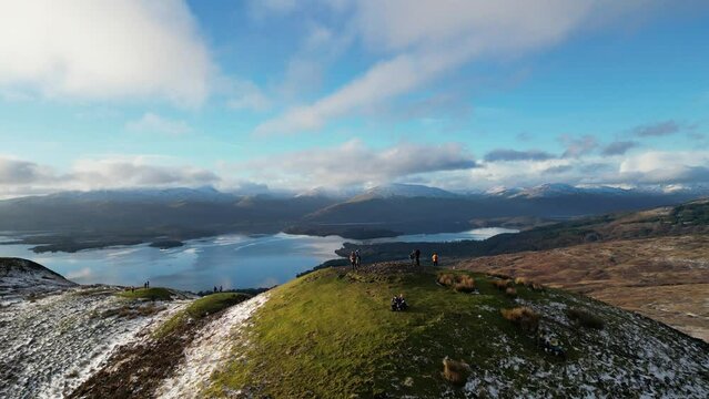 Drone footage of people standing on the Conic hill overlooking the Loch Lomond,in Stirling Scotland.
