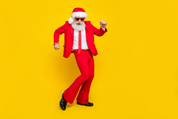 Fototapeta na wymiar Full length photo of cheerful positive retired guy wear red tux claus hat dancing empty space isolated yellow color background