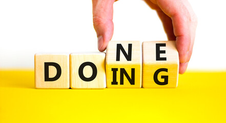 Doing and done symbol. Concept words Doing Done on wooden block. Beautiful yellow table white background. Businessman hand. Business doing and done concept. Copy space.