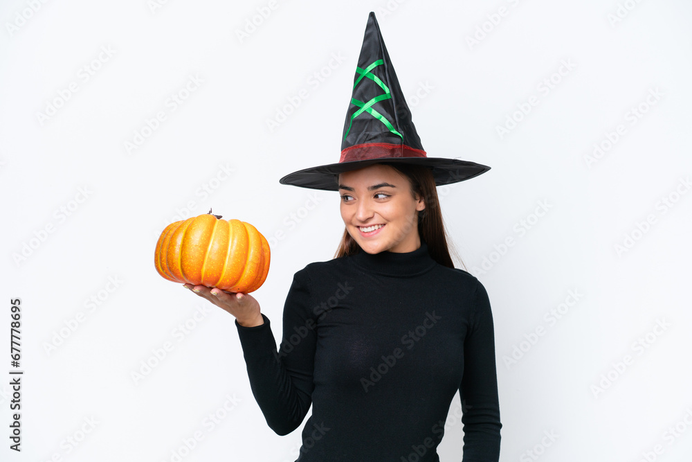 Poster Young caucasian woman costume as witch holding a pumpkin isolated on white background with happy expression