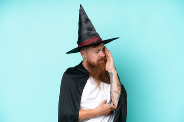 Young wizard in halloween isolated on blue background with headache