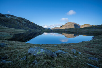 The mountains Great End, Great Gable and Green Gable reflected in the waters of Sprinkling Tarn in the lake district, Cumbria, England.