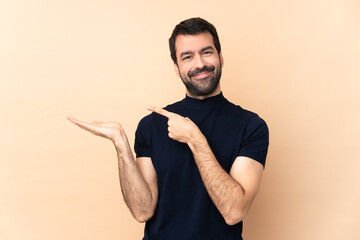 Caucasian handsome man over isolated background holding copyspace imaginary on the palm to insert...