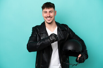 Young caucasian man with a motorcycle helmet isolated on blue background celebrating a victory