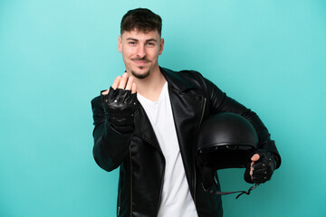 Young caucasian man with a motorcycle helmet isolated on blue background inviting to come with hand. Happy that you came