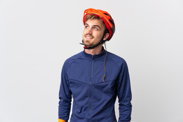 Young cyclist blonde man isolated on white background thinking an idea while looking up