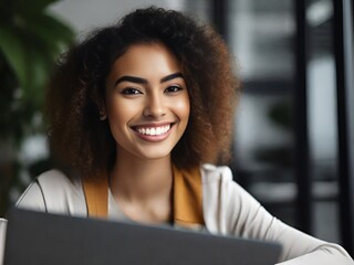 a young smiling beautiful woman is working at a laptop in the office