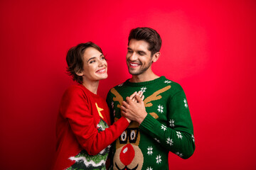 Photo of excited dreamy husband wife dressed ugly pullovers embracing isolated red color background