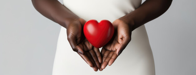 Female hands holding red heart. Love, care and charity concept. Dark skinned woman in white dress...