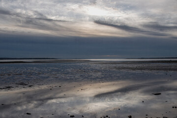 deserted beach at Hill Head with stormy Autumn sky and clouds reflecting in the water