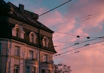Beautiful shot of an old building seen behind electricity wires at pink sunset
