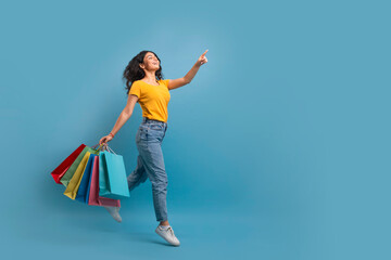 Excited young indian woman shopaholic walking with purchases