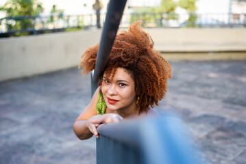 Beautiful red-haired woman standing next to an iron railing in a square.