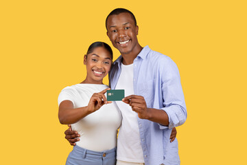 Happy black couple holding credit card together, smiling