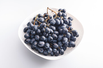 Bunches of blue grapes on a white plate. Healthy eating, winemaking, summer harvest, vineyard