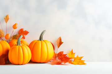 Naklejka na ściany i meble Autumn ambiance: Orange pumpkins and fall leaves on a light surface, creating a warm and seasonal background.