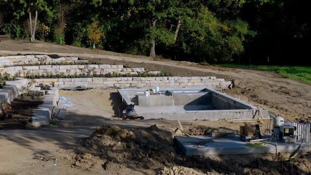 Construction site, construction of a swimming pool near a private house. Drone wide shot. 
