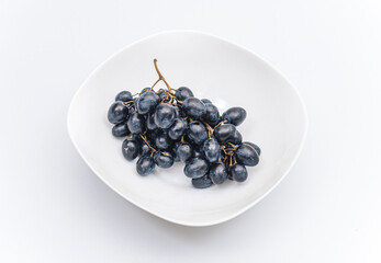 Bunches of blue grapes on a white plate. Healthy eating, winemaking, summer harvest, vineyard