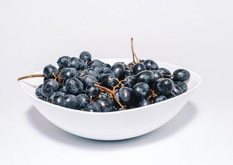 Bunches of blue grapes on a white plate. Healthy eating, winemaking, summer harvest, vineyard